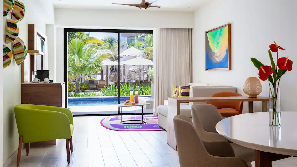 Separate living room with sleeper sofa and swim-up pool views in the Club One Bedroom Master Swim-Up Suite.